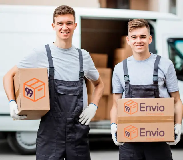Duas pessoas de macacão segurando caixas de papelão com a marca 99 Envio, em frente a uma van aberta com mais caixas